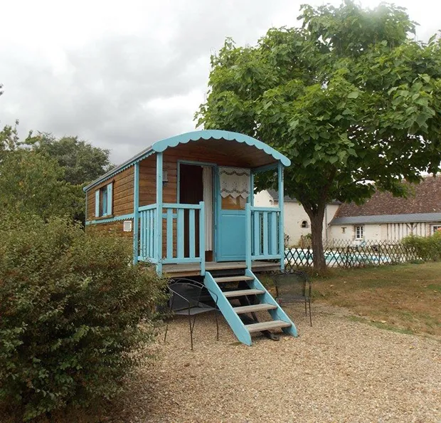 Roulotte en bois bleue et marron avec un porche, dans un cadre verdoyant à Autrèche près de Tours et Amboise en Indre-et-Loire 37
